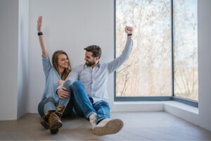 A man and a lady raising both raisng one hand and smiling