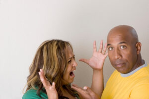 A woman holding her hands in frustation with a man stading infront
