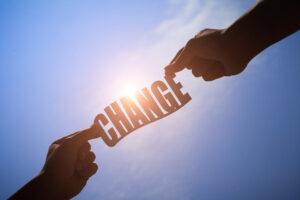 hands holding the word change in front of a blue sky 