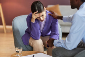 A man consoling a woman sitting on a sofa