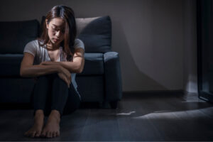 a person sitting on the floor in front of a couch in a dark room