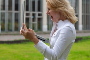a person in a white shirt holding a laptop in frustration