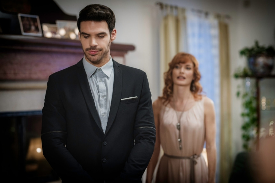 A man in black suit and a woman behind him