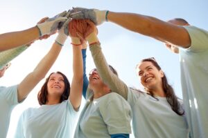 a group of people in blue shirts holding up their hands