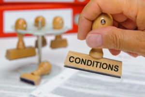 a rubber stamp with the word conditions on it in front of a stack of papers