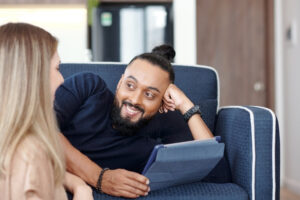 Two people sitting on a couch looking at a tablet