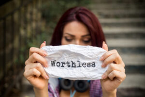 a person holding a piece of paper with the word worthless written on it