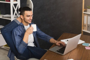 a person sitting in front of a laptop with their legs stretched out