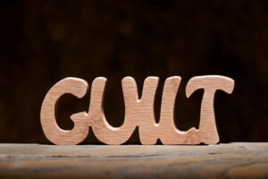 The word 'guilt' is made out of wooden blocks on a wooden table