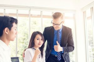 Three people in business attire; one thumbs up for the only lady.