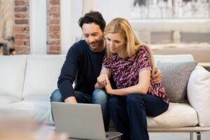 Two people sitting on a couch looking at a laptop
