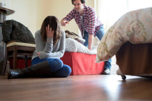 A woman holding down her head with the man behing arguing.