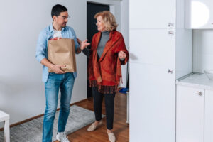 Two people standing in a kitchen holding a bag
