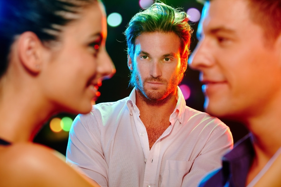 Someone looking from thr background at a man and a woamn looking at each other