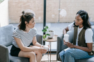 Two individuals sitting on couches talking to each other.