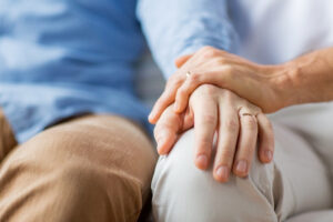 two people holding hands while sitting on a couch
