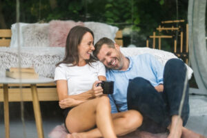 A person and another person sitting on the floor with a cup of coffee