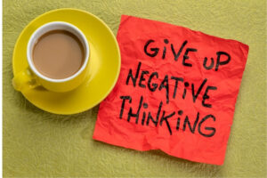  A cup of coffee with a paper saying Give Up Negative Thinking