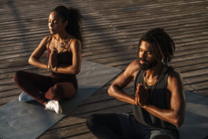 Two people doing yoga on a dock