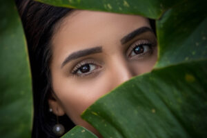 A lady's face behind the covers of leaves.