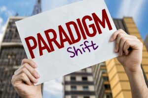 Two hands raising a placard written 'paradigm shift'