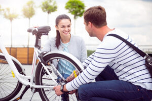 A man and a woman squatting next to a bicycle