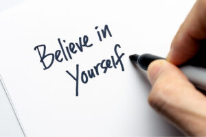 An image of ahand writng the words 'Believe in Yourself'