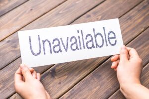 Two hands showing the word 'Unavailable" written on a white card.