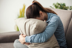 a person is sitting on a couch and hugging a pillow
