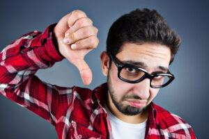 a person with glasses and a red plaid shirt is making a thumbs down sign