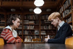 two people playing chess in a library