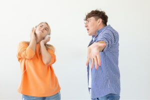 A woman using headphines to block hearing from the man's yelling.