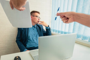 A hand pointing to man looking away at the desk.