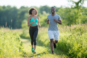 Two people jogging through a grassy field