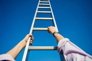 a person reaching up to the top of a ladder