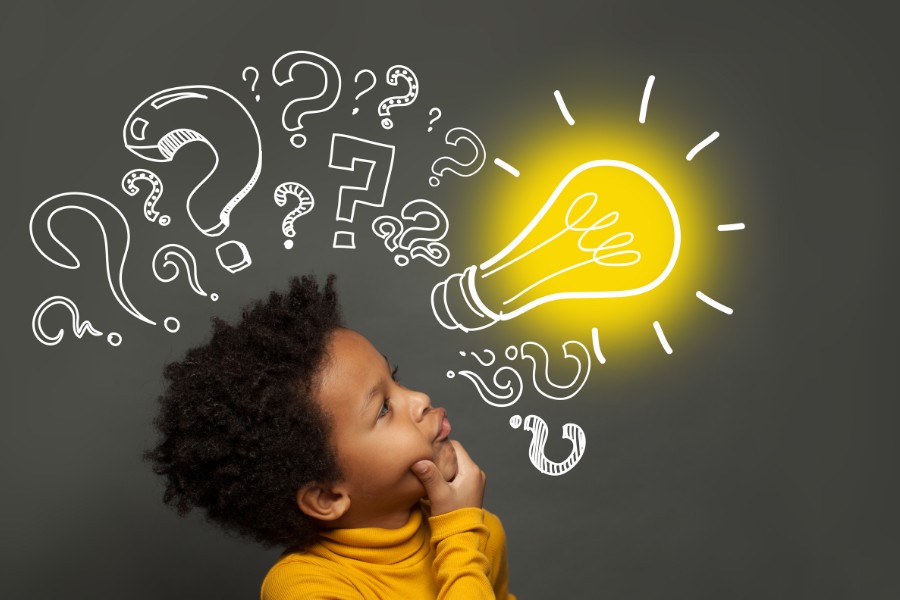 Child looking up at question marks and a glowing lightbulb drawing.