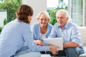 a man and woman sitting on a couch with an older couple looking at a tablet