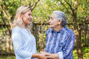 An old woman and a younger lady holding hands with another person in the garden