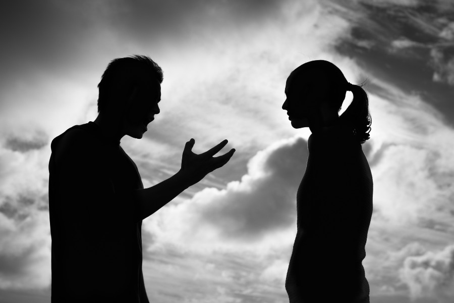 silhouette of a person and another person talking in front of a cloudy sky