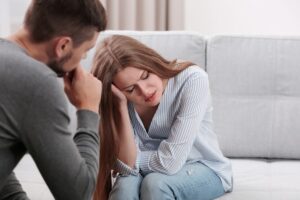 A person and another person sitting on a couch looking at each other