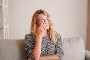 a person sitting on a couch with their hands on their face