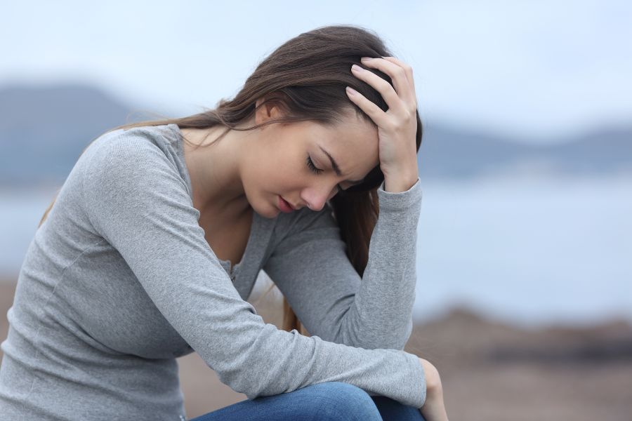 a person sitting on the ground with their head in their hands