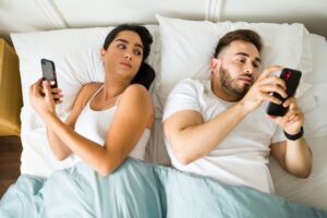 a person and person laying in bed looking at their phones