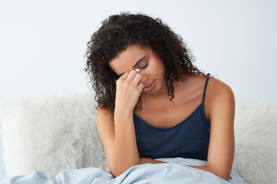 a person sitting in bed with their head in their hands