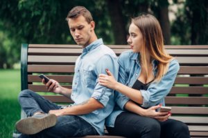 A man holding a phone and a woman sitting beside him while touching his arm