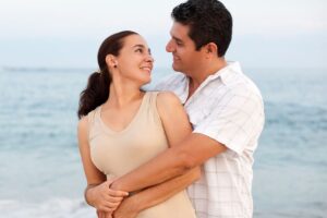 a couple embrace on the beach in front of the ocean