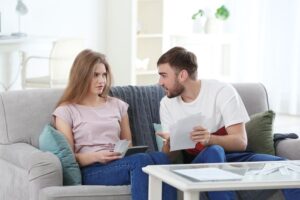 Two people sitting on a couch looking at papers