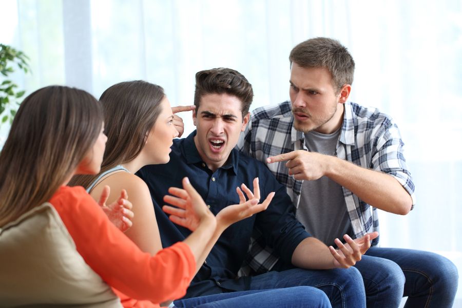 Two couples engaged in a heated argument, both men pointing fingers at the other man's head.