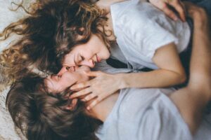 Two people laying on the floor with their arms around each other