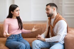 Two people sitting on a couch talking to each other